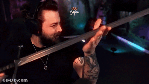 Man With Tattoo Holding Sword In Front Of Caliban Screen GIF