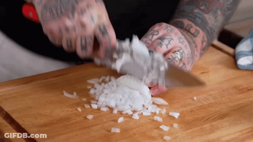 Man With Tattoos Cutting Onions On Wooden Cutting Board GIF