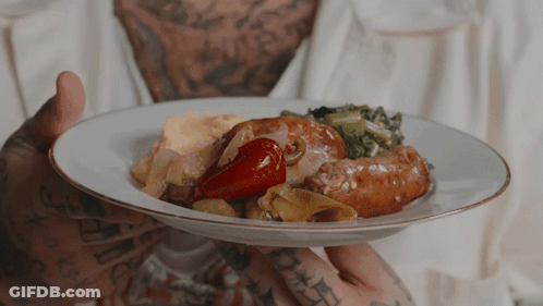 Man With Tattoos Holding Plate Of Food With Sausage And Vegetables GIF