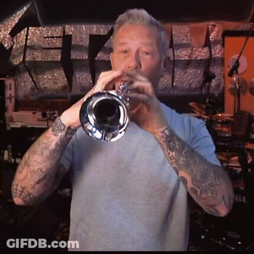Man With Tattoos Playing Trumpet In Dark Room GIF
