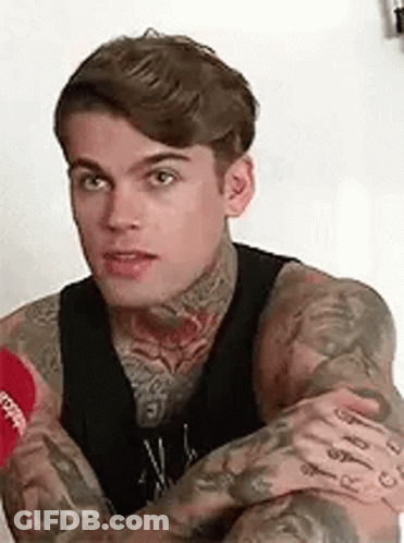 Man With Tattoos Sitting With Arms Crossed GIF