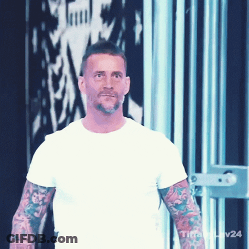 Man With Tattoos Wearing White T-Shirt In Front Of Wall With Number 24 GIF