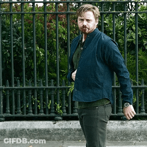 Man With Watch Standing In Front Of Metal Fence GIF