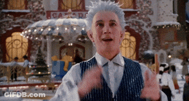 Man With White Hair And Blue Vest In Front Of Gingerbread Building GIF