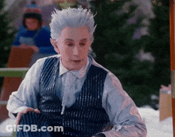 Man With White Hair And Blue Vest Sitting In Snow GIF