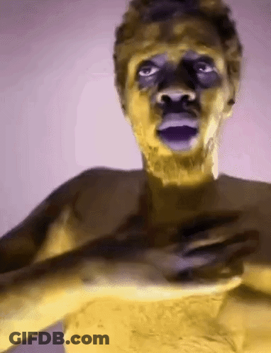 Man With Yellow Paint On Face Holding Hands To Chest GIF