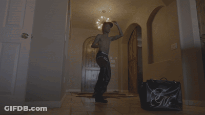 Man Without Shirt Dancing In Hallway Next To Bag Saying GM GIF