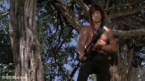 Man Without Shirt Holding Gun In Tree GIF