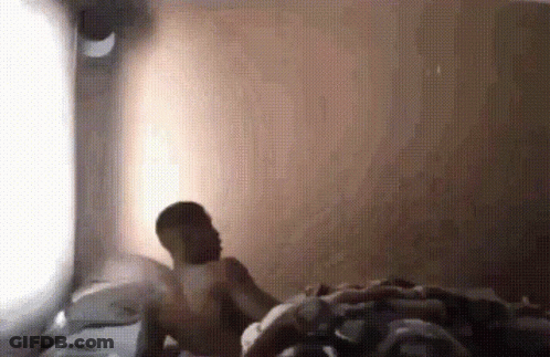 Man Without Shirt Laying On Bed In Front Of Window GIF
