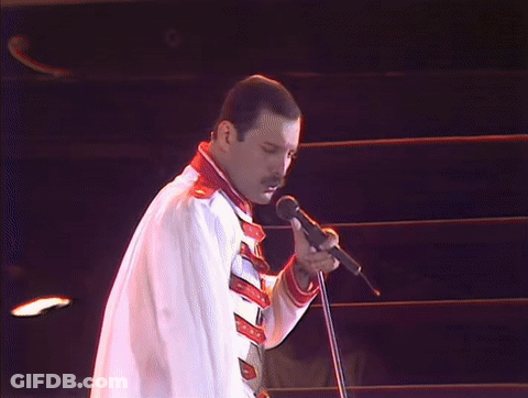 Man Without Shirt Singing Into Microphone Holding Flag GIF