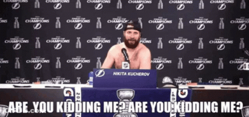 Man Without Shirt Sitting At Table In Front Of Champions Wall GIF