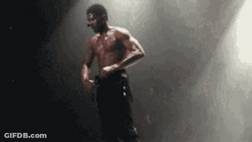 Man Without Shirt Standing At Microphone On Stage GIF