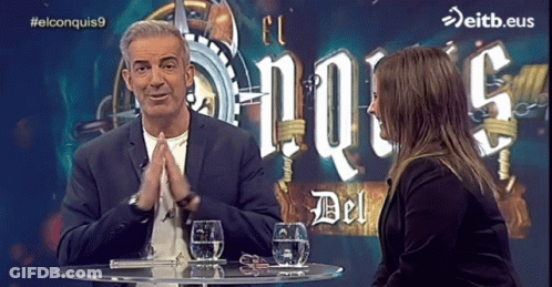 Man Woman At Table With El Conquistas9 Sign GIF