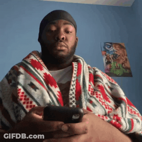 Man Wrapped In Colorful Blanket Looking At Phone GIF