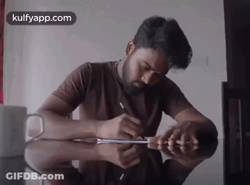 Man Writing At Table With Kulfyapp Logo GIF
