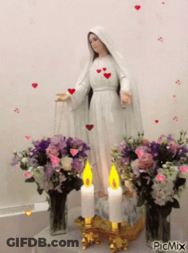 Mary Statue Surrounded By Flowers And Candles GIF