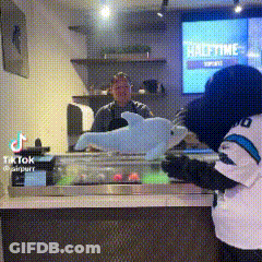 Mascot Holding Stuffed Dolphin In Front Of Halftime Sign GIF