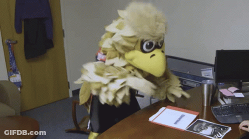 Mascot In Bird Costume Sitting At Desk GIF