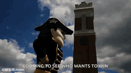 Mascot In Front Of Clock Tower Saying Looking To See Who Wants To Win GIF