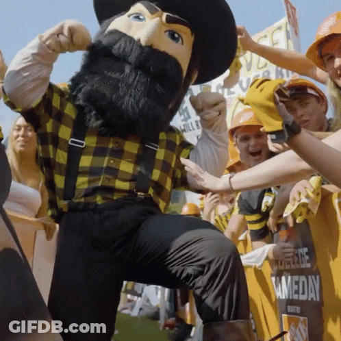 Mascot In Plaid Shirt And Suspenders In Front Of Crowd GIF