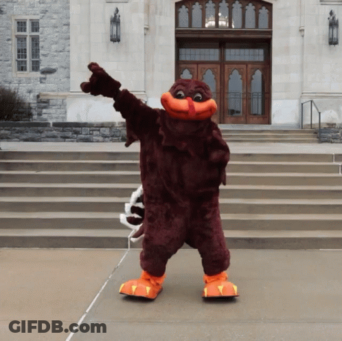Mascot Standing In Front Of Building Pointing GIF