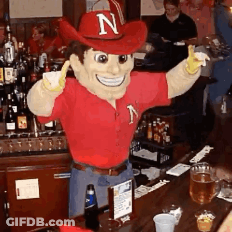 Mascot With Letter N On Hat Standing At Bar GIF