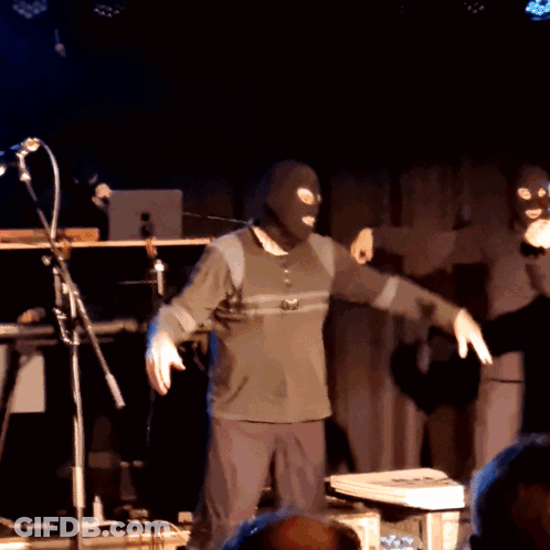 Masked Man Dancing On Stage With Microphone GIF