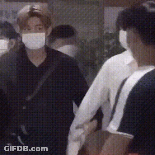 Masked Man Holding Another's Hand In Crowd GIF