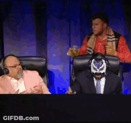 Masked Man In Chair With Suited Man Behind GIF