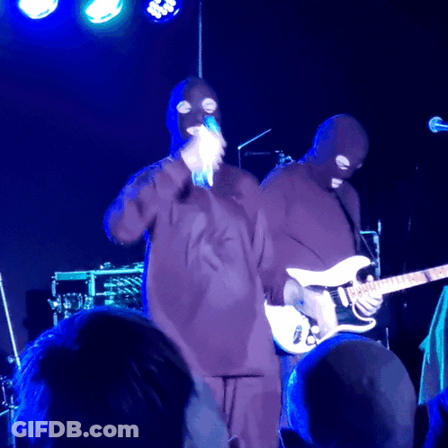 Masked Man Singing Into Microphone Playing Guitar GIF