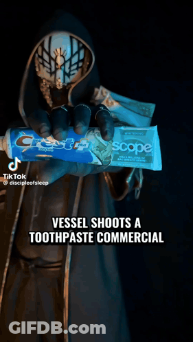 Masked Person Holding Crest Toothpaste GIF