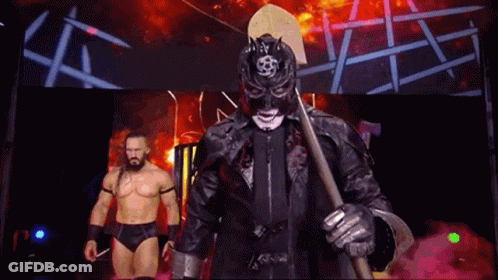 Masked Wrestler Holding Axe With Another Wrestler Behind GIF
