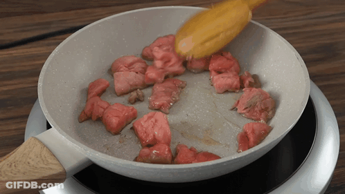 Meat Is Being Cooked In A Pan On A Stove GIF