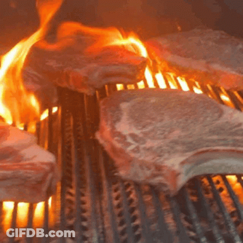 Meat Is Being Cooked On A Grill With Flames Coming Out Of It GIF