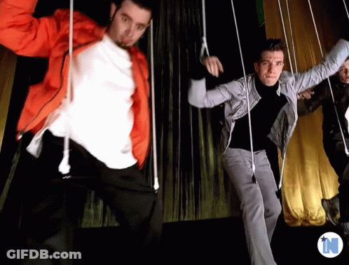 Men Dancing In Front Of Yellow Curtain With Letter N GIF
