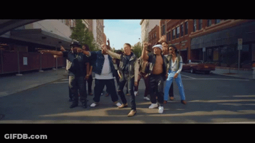 Men Dancing On Street In Front Of Brick Building GIF