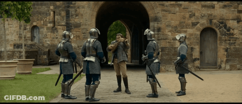 Men In Armor Standing Before Stone Building GIF