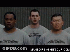 Men In Gray Police Academy Shirts Standing In Line GIF