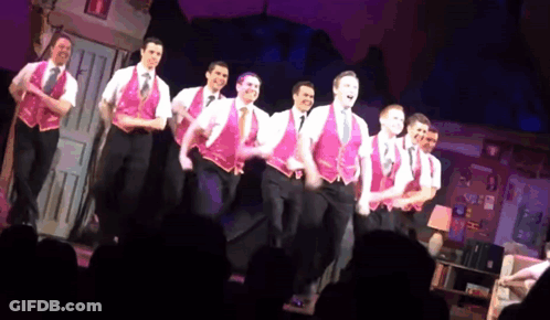 Men In Pink Vests Dancing On Stage GIF