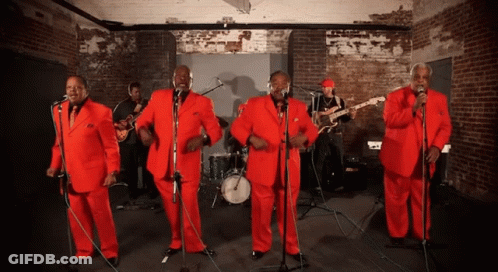 Men In Red Suits Singing Into Microphones GIF