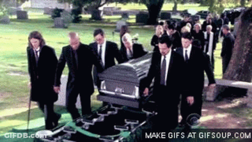 Men In Suits Carrying Coffin In Cemetery GIF