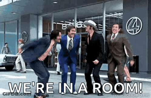 Men In Suits Dancing In Front Of Building Saying We're In A Room GIF