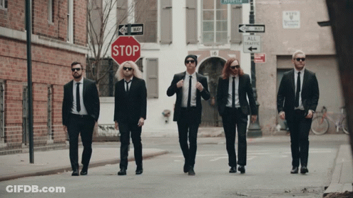 Men In Suits Walking Past Stop Sign GIF