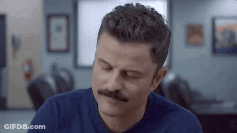 Men Laying On Bed With Sign Saying The Bed GIF