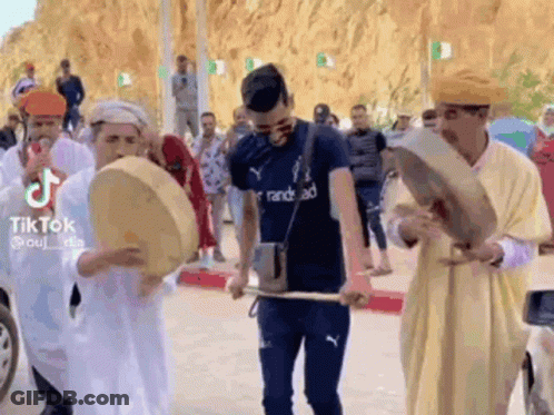 Men Playing Drums On Street For Crowd GIF