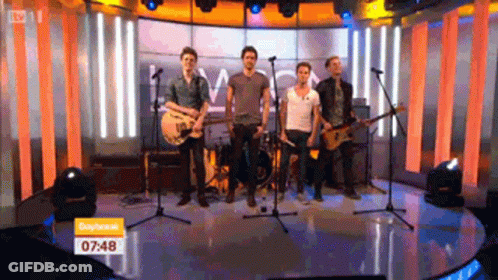 Men Playing Guitars On Stage At 7:48 GIF