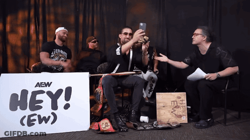 Men Sitting In Front Of Hey (Ew) Sign GIF