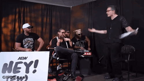 Men Sitting In Front Of Hey Sign GIF