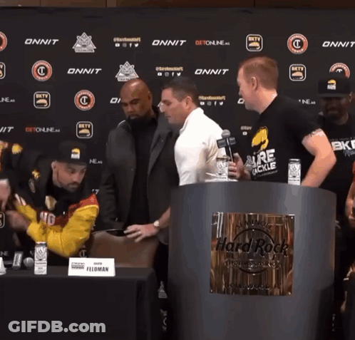 Men Standing Around Hard Rock Sign GIF
