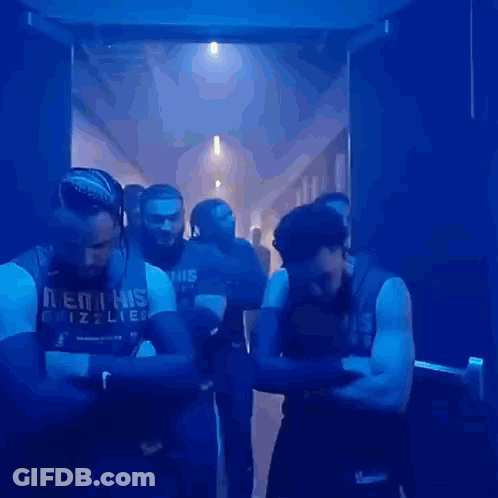 Men Standing Crossed Arms In Dark Hallway GIF